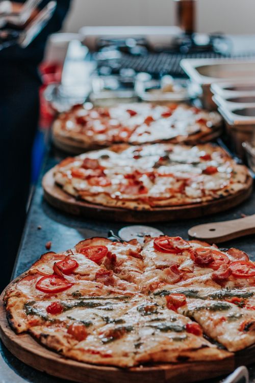Free Wood-fired pizzas with fresh toppings ready to serve in a cozy restaurant setting. Stock Photo