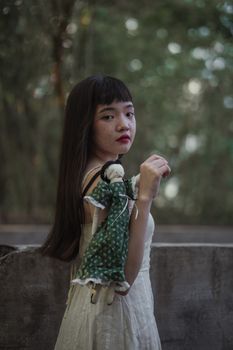 一个亚洲女孩抱着洋娃娃，在宁静的森林氛围中伫立，流露出孤独与内省
