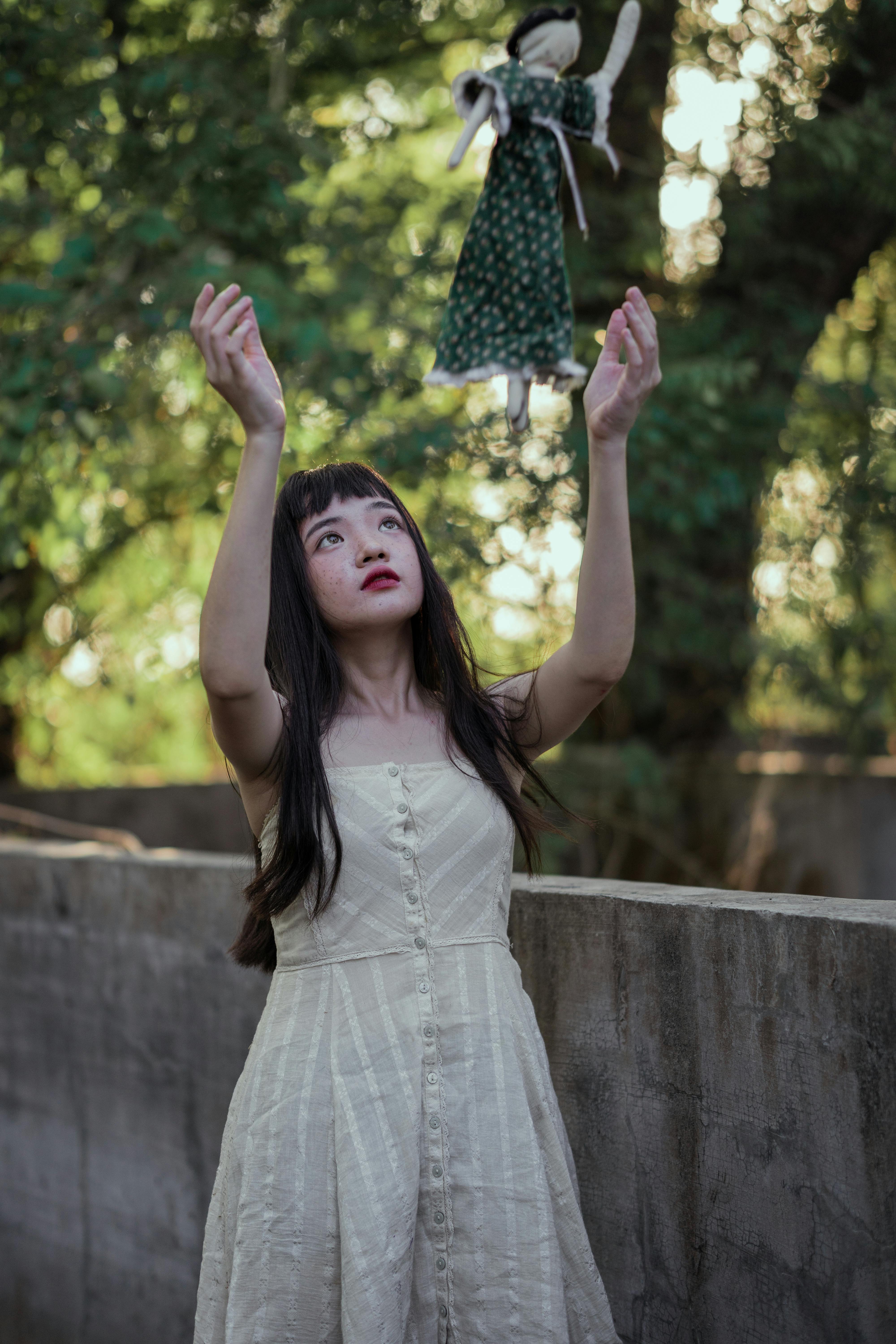 girl in a dress throwing a doll