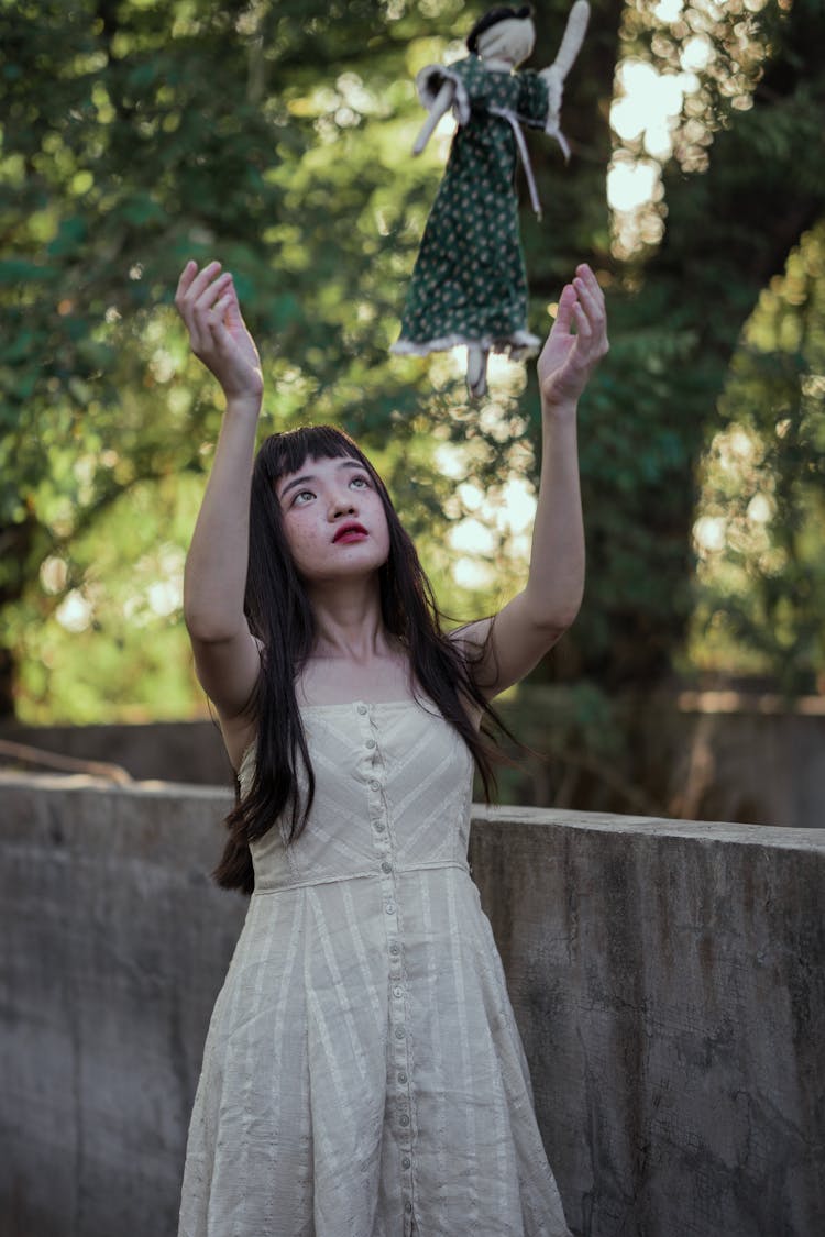 Girl In A Dress Throwing A Doll