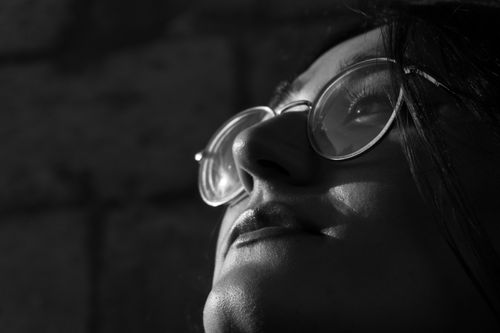 Free Close-up black and white portrait of a woman wearing glasses, gazing upwards in thought. Stock Photo