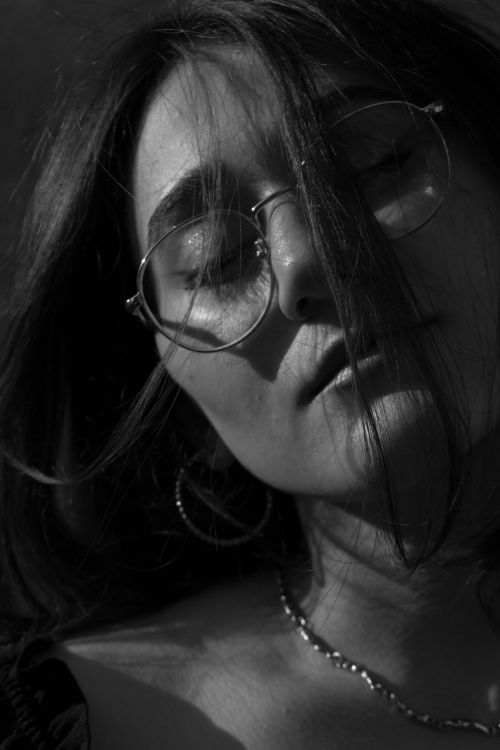Free Artistic black and white portrait of a woman with glasses and relaxed expression. Stock Photo