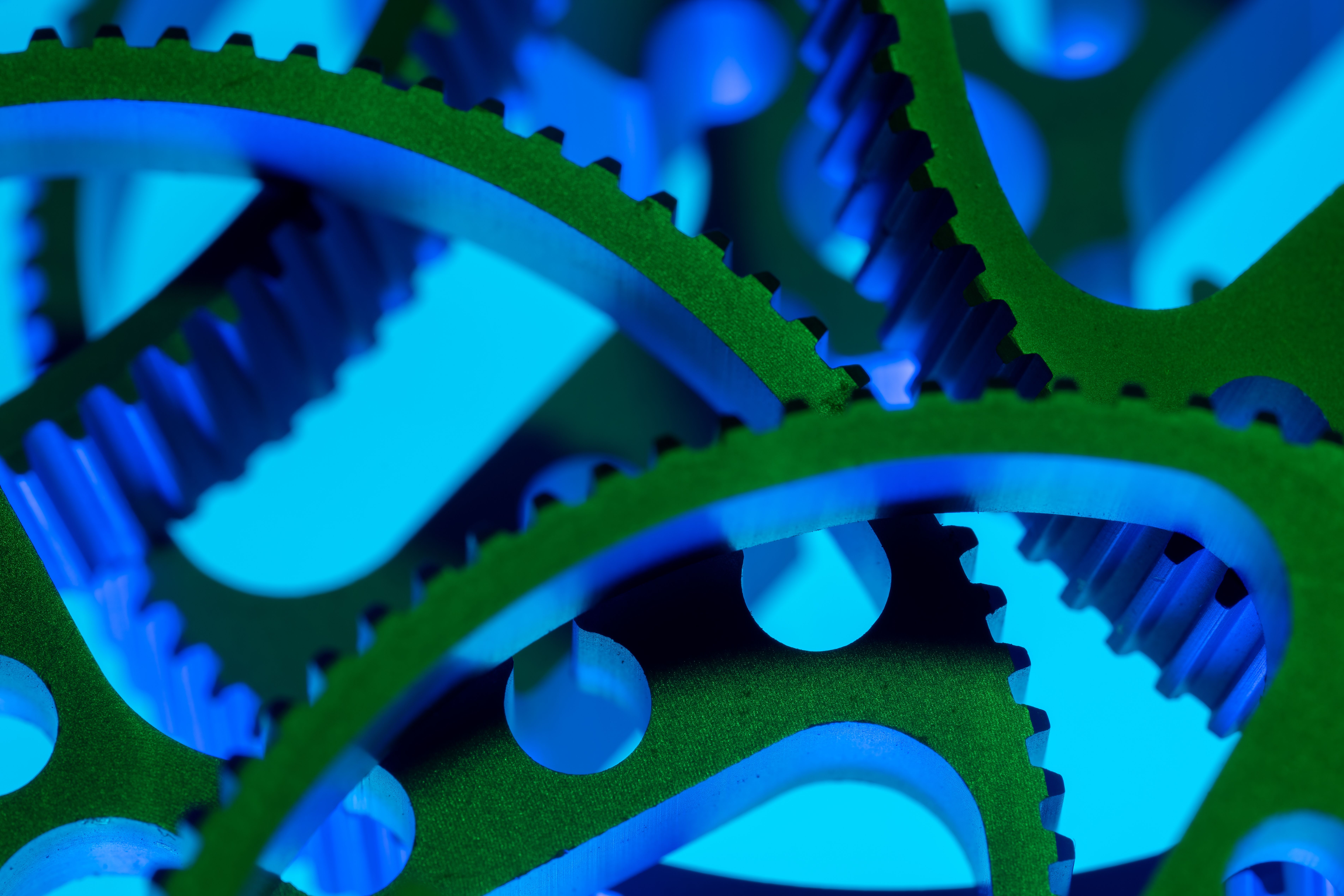 Vibrant macro shot of green and blue interlocking gears showcasing precision engineering.