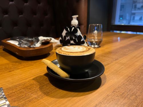 Free A cup of cappuccino with biscuit on a wooden table in a Dhaka cafe, offering a warm and inviting vibe. Stock Photo