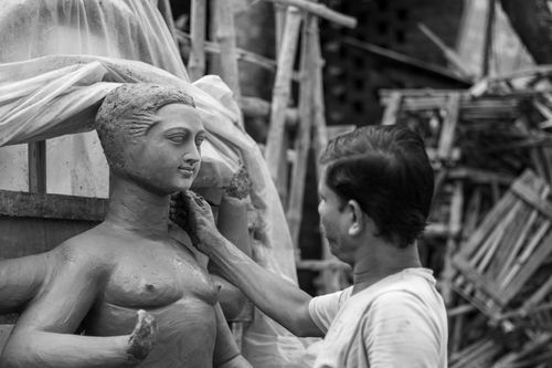 Free An artist skillfully sculpts a traditional clay idol, showcasing craftsmanship and cultural heritage. Stock Photo