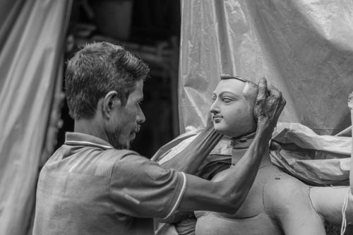 Free A skilled artisan works meticulously on a clay statue, showcasing traditional craftsmanship indoors. Stock Photo