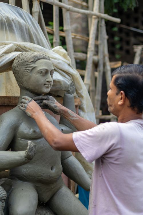 Free A skilled artisan carefully shaping a clay idol for cultural celebrations. Stock Photo