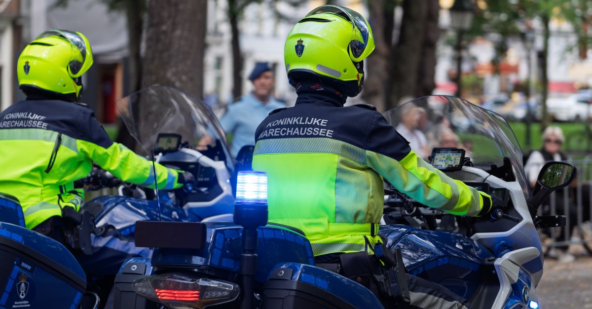 Royal Netherlands Marechaussee officers on patrol with motorcycles in an urban area.