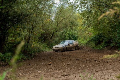 Free A rally car speeds through a muddy forest track, showcasing off-road adventure. Stock Photo