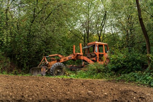 Free An old rust-colored bulldozer sits idle in a forest clearing in Województwo Małopolskie, Poland. Stock Photo