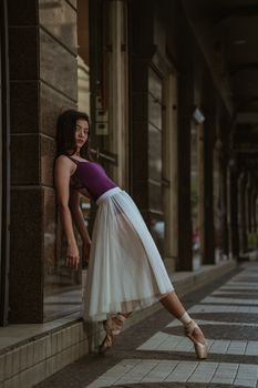 一位芭蕾舞演员身着薄纱裙，优雅地倚在户外的柱子上，散发着时尚与创造力