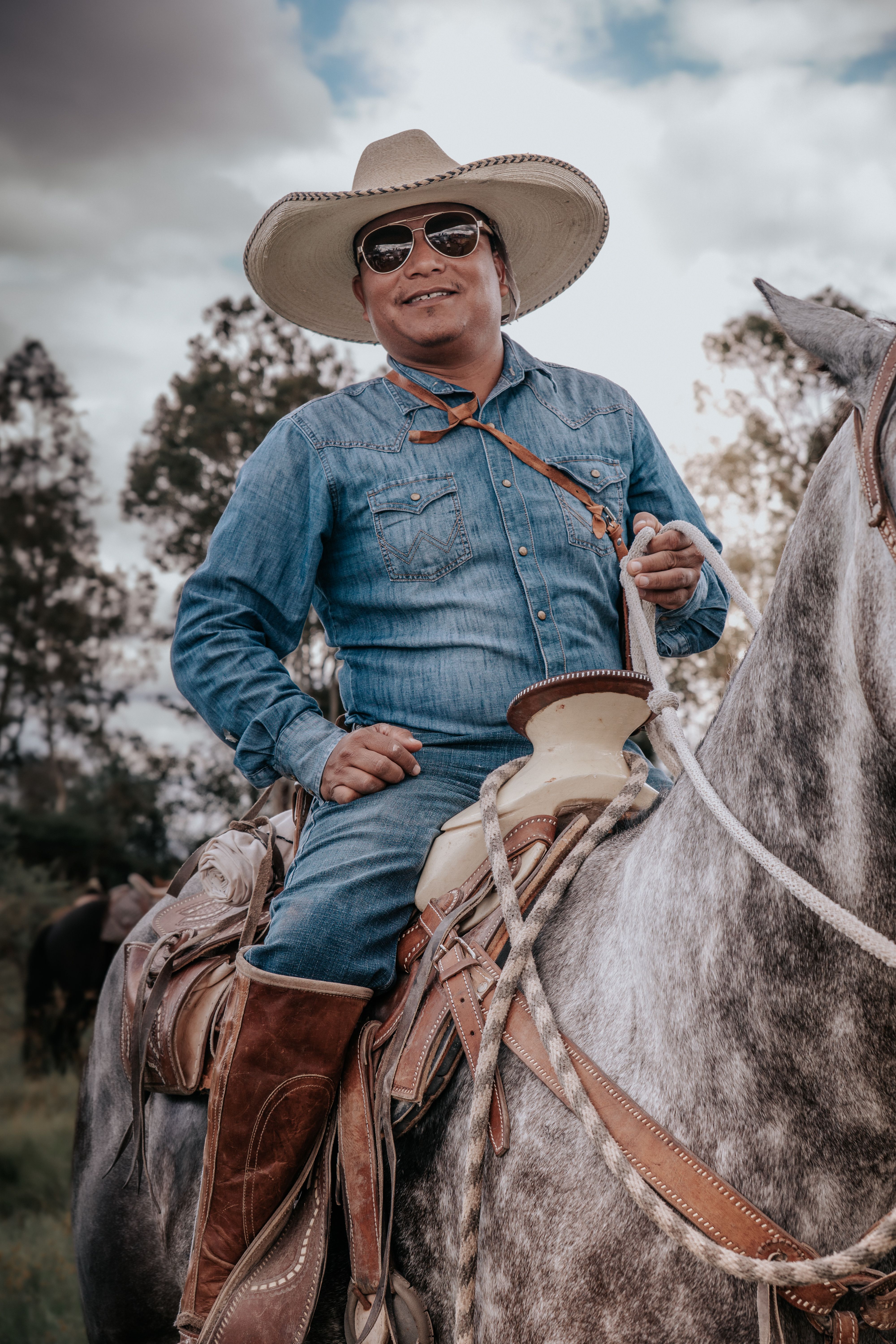 A traditional charro in denim and cowboy hat riding gracefully on a horse in Guanajuato, Mexico.