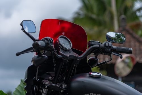 Free Close-up of a motorcycle's handlebars and red windshield, outdoors. Stock Photo