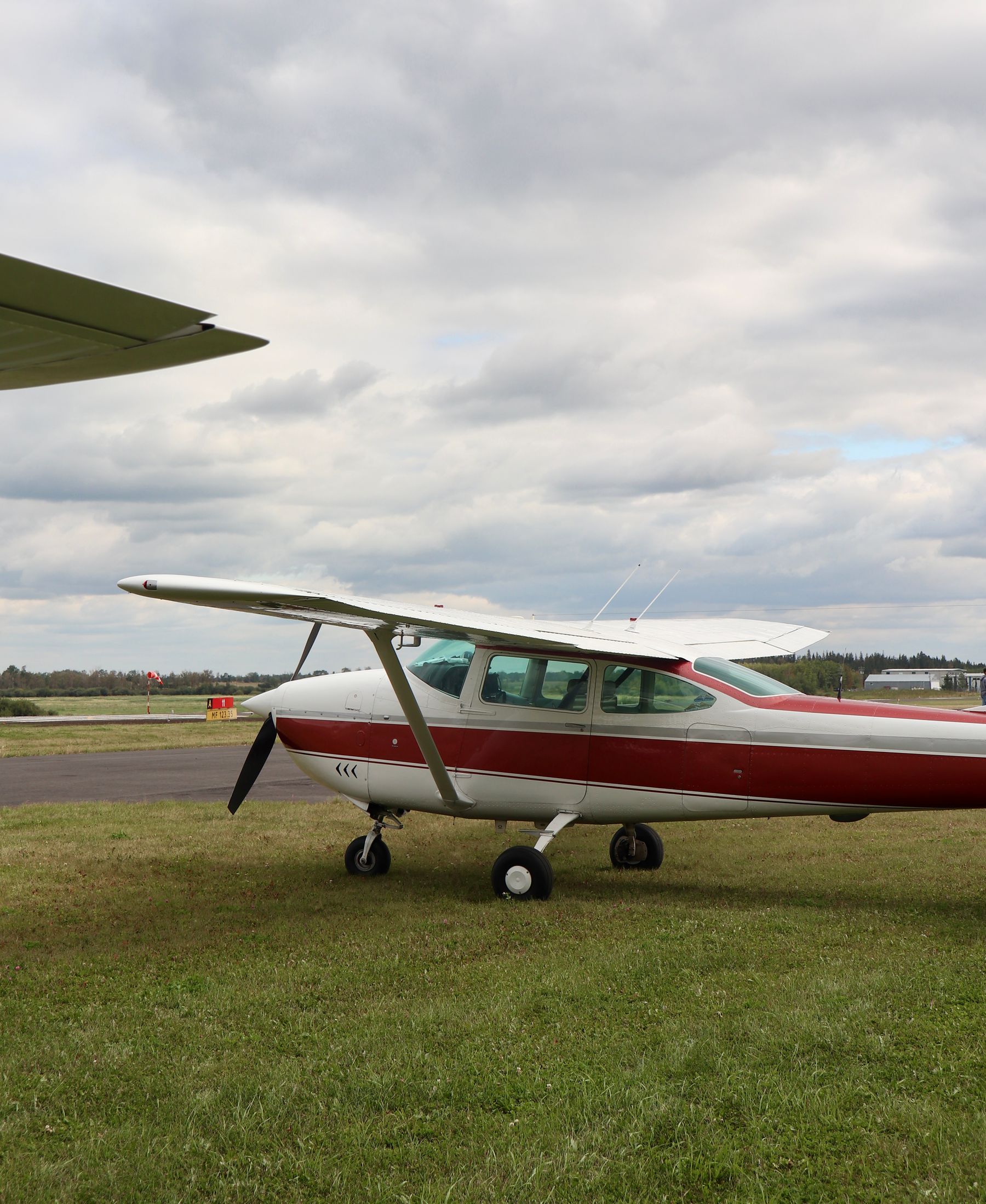 A red and white Cessna parked on a grass airfield