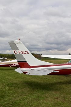 Small aircraft parked on a grassy field under cloudy skies in Sherwood Park, AB, Canada.