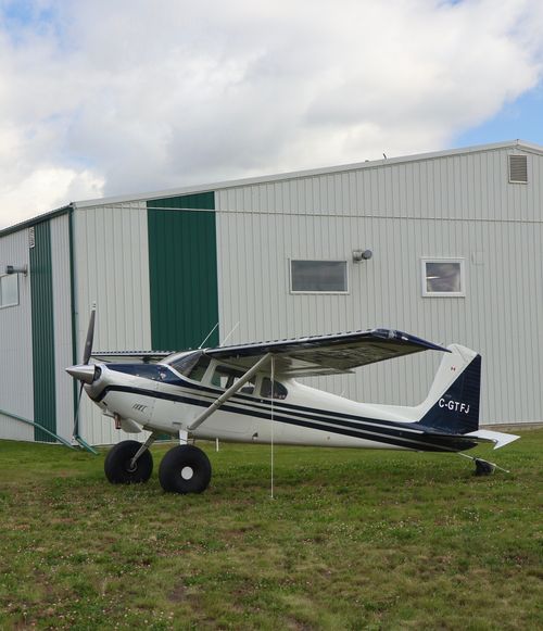 Free A light aircraft parked outside a hangar in Sherwood Park, Alberta, under a partly cloudy sky. Stock Photo