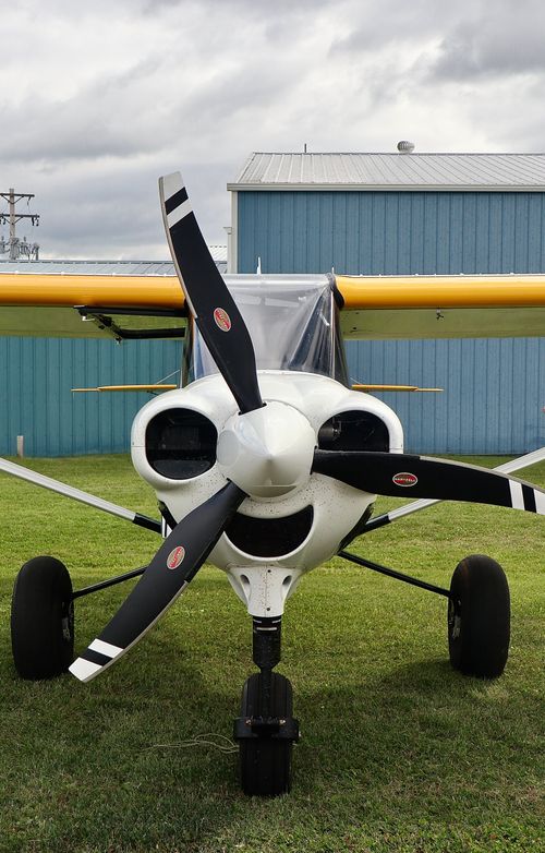Free Front view of a light aircraft on grass outside a blue hangar in Sherwood Park, AB. Stock Photo