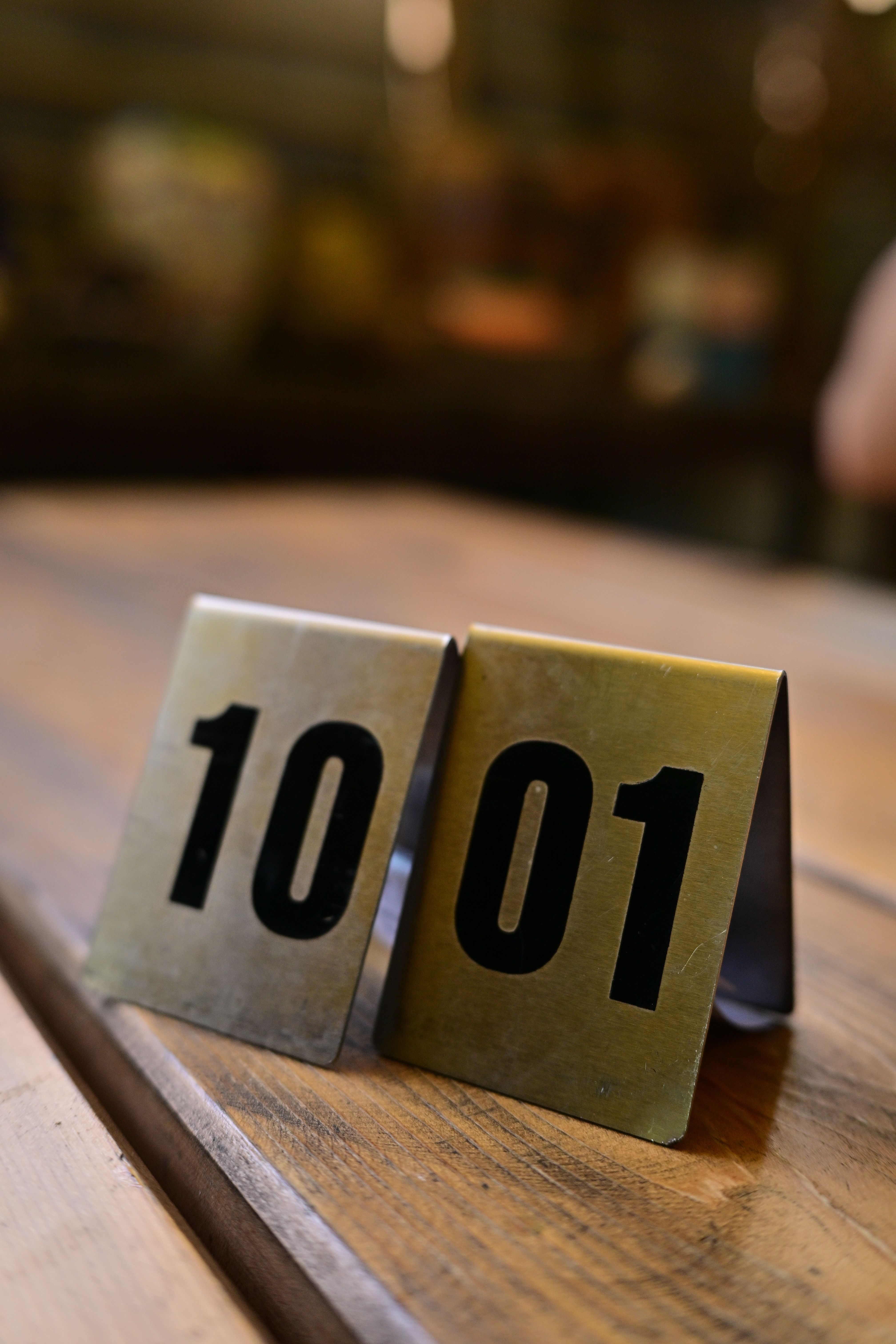Close-up of numbered table markers on a wooden table in a cozy indoor setting.
