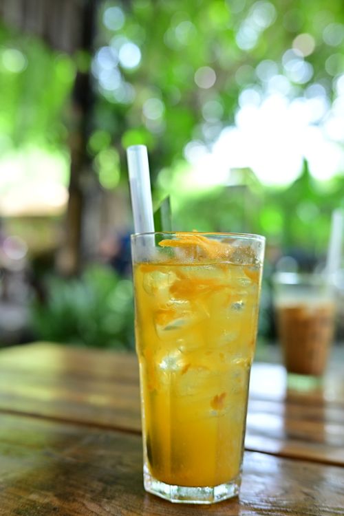 Free A glass of citrus iced tea with ice cubes, served on a wooden table outdoors. Stock Photo