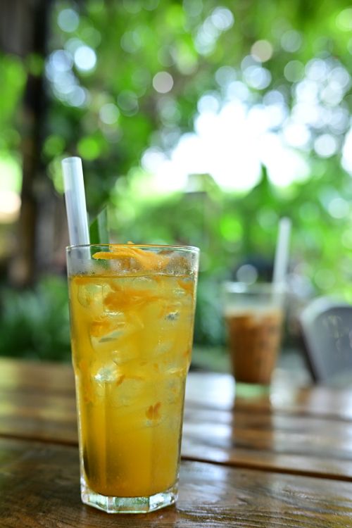 Free A chilled glass of iced tea with a straw, set against a blurred green background, perfect for a summer refreshment. Stock Photo