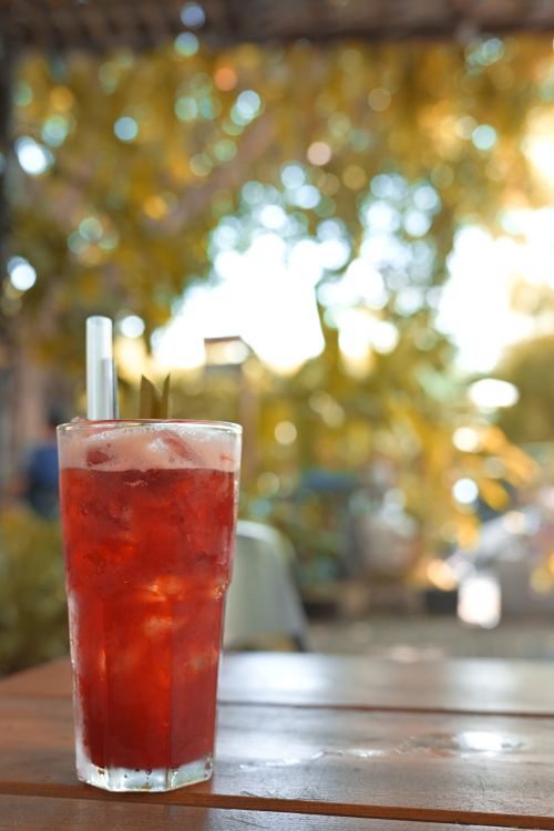 Free Fresh iced red beverage with straw on a sunny outdoor patio. Stock Photo