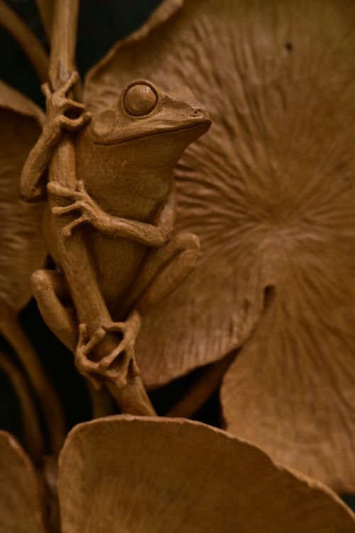 Free Detailed close-up of a brown frog sculpture amid textured leaves. Stock Photo