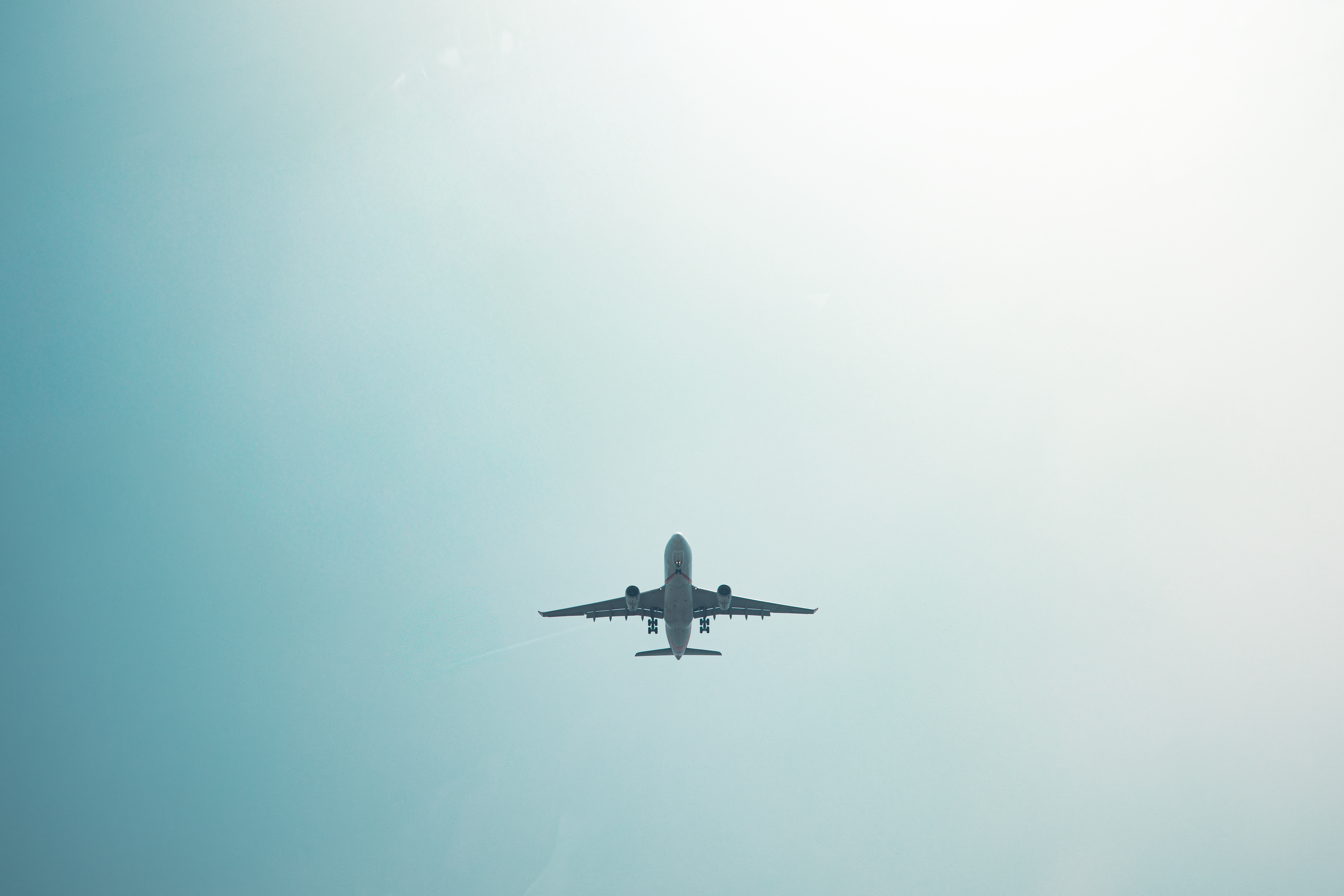 Airplane flying overhead in clear blue sky, perfect for travel themes. — lounges at Zhuhai Airport