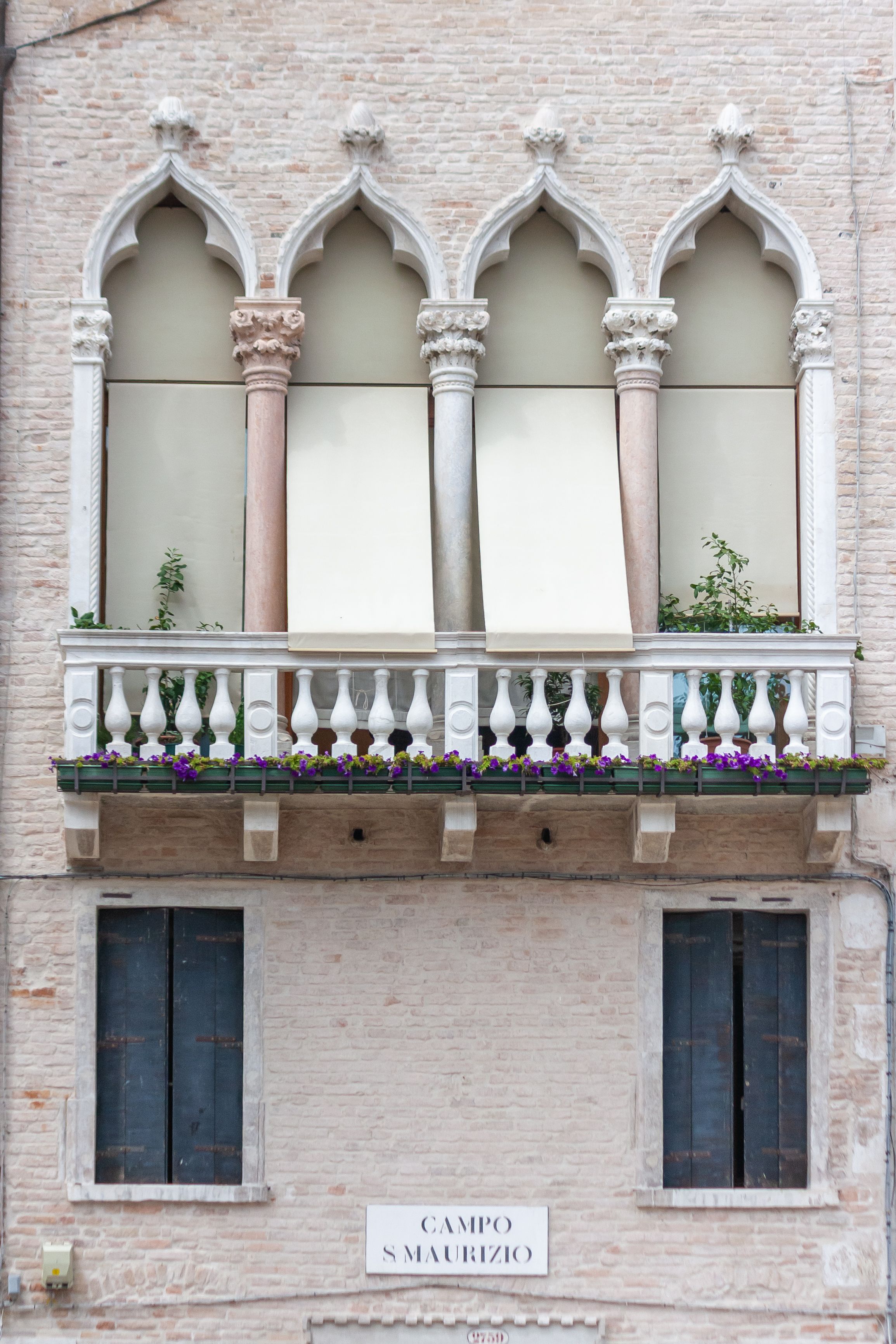 A beautiful Venetian balcony with Gothic arches and flowers in Campo Santo Maurizio, Venice.
