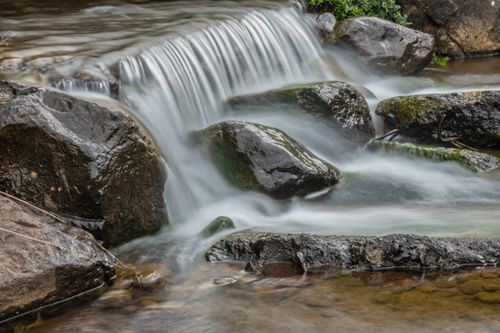 Free A serene small waterfall cascading over smooth rocks in a natural outdoor setting. Stock Photo