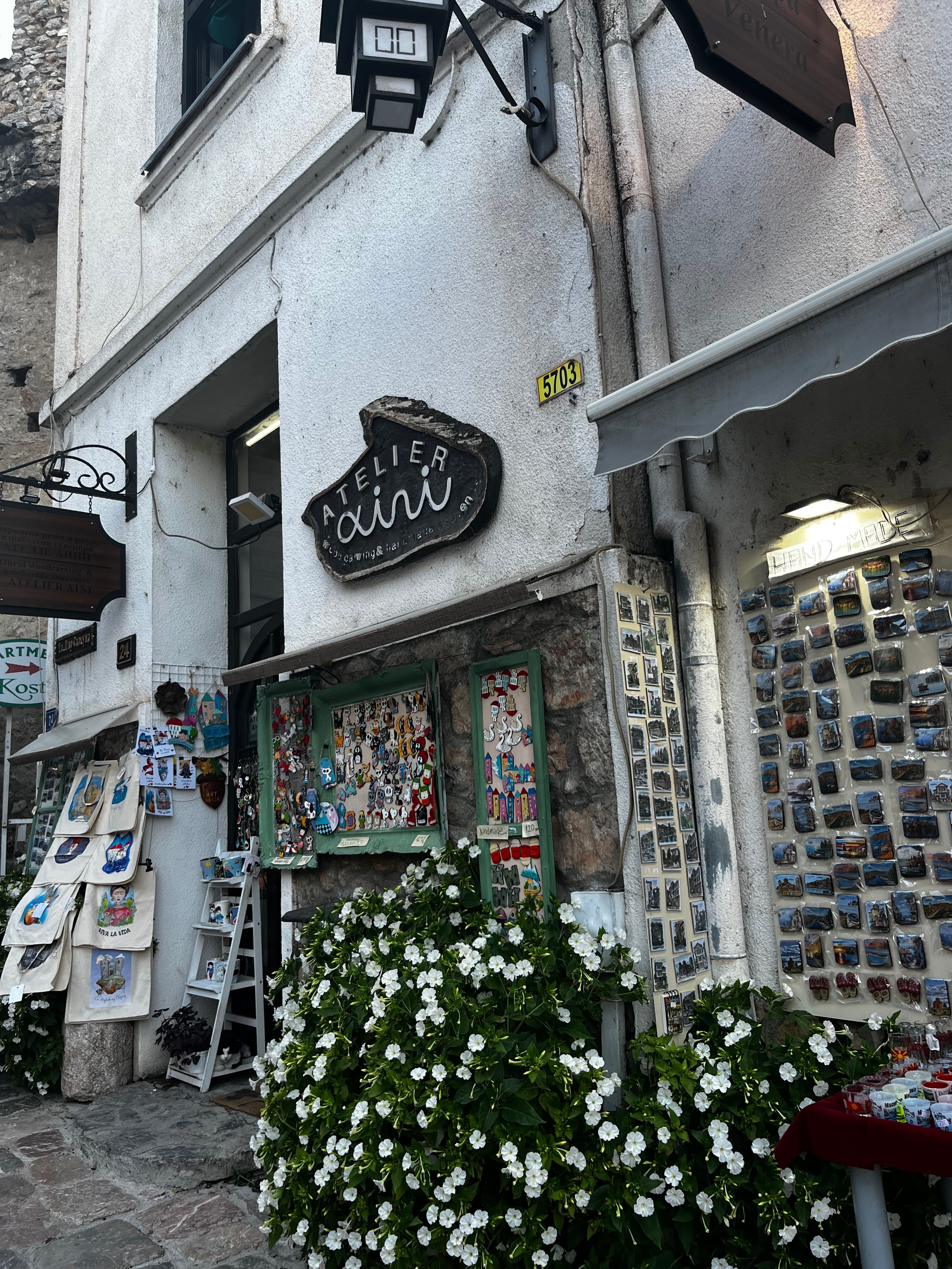 A quaint artisan shop with decorative magnets and flowers on a rustic street corner.