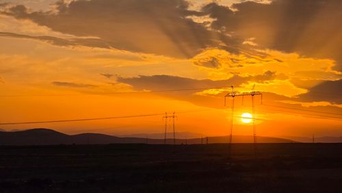 Free Stunning golden sunset over the mountains with electric towers silhouetted against the sky. Stock Photo