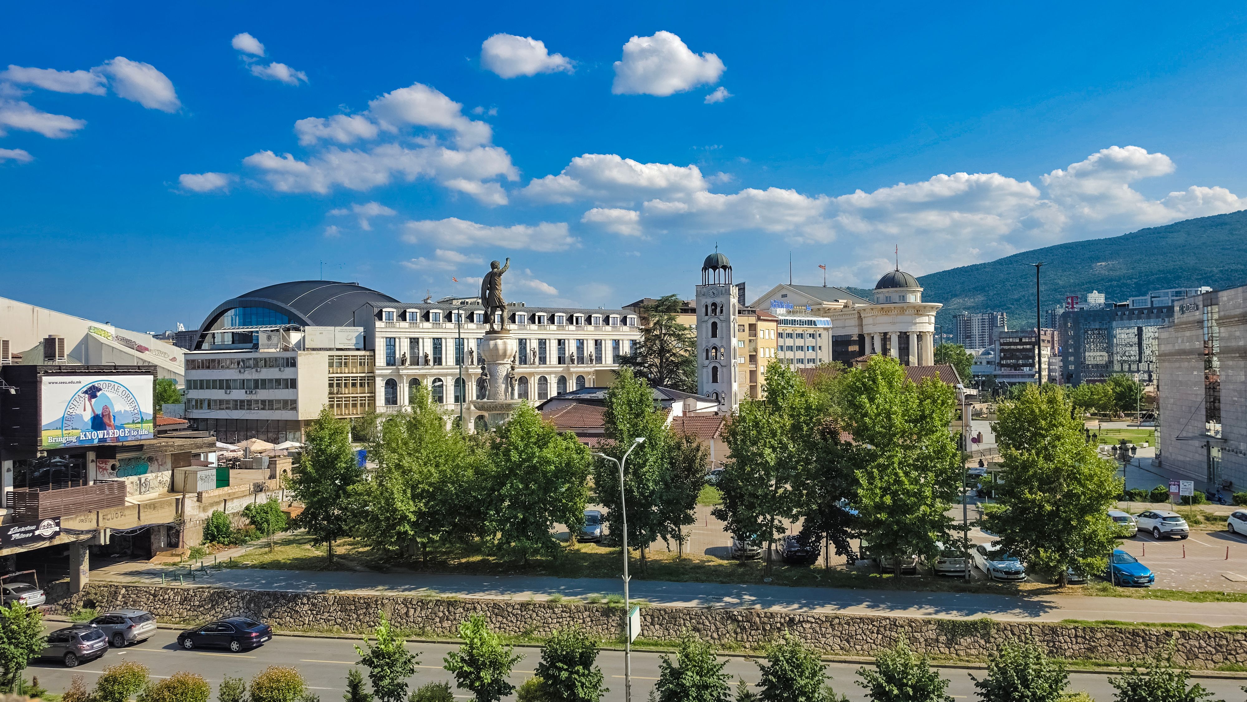 Cityscape of Skopje featuring the iconic Alexander the Great statue on a bright summer day.