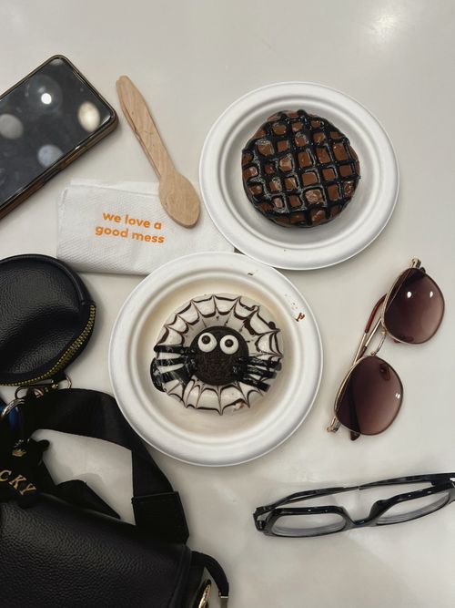 Free A fun spider-themed cookie and chocolate pastry on a white plate with accessories. Stock Photo