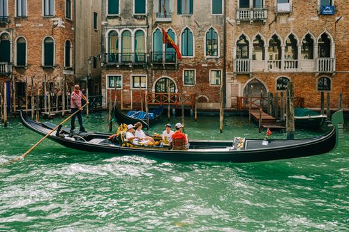 Free Gondola gliding through the picturesque canals of Venice with classic architecture. Stock Photo