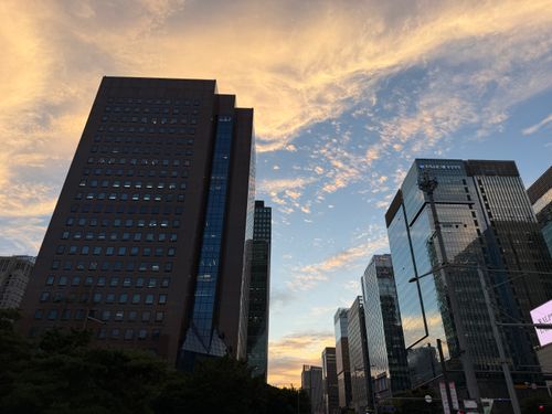 Free Dramatic city skyline with modern skyscrapers under a vibrant sunset sky. Stock Photo
