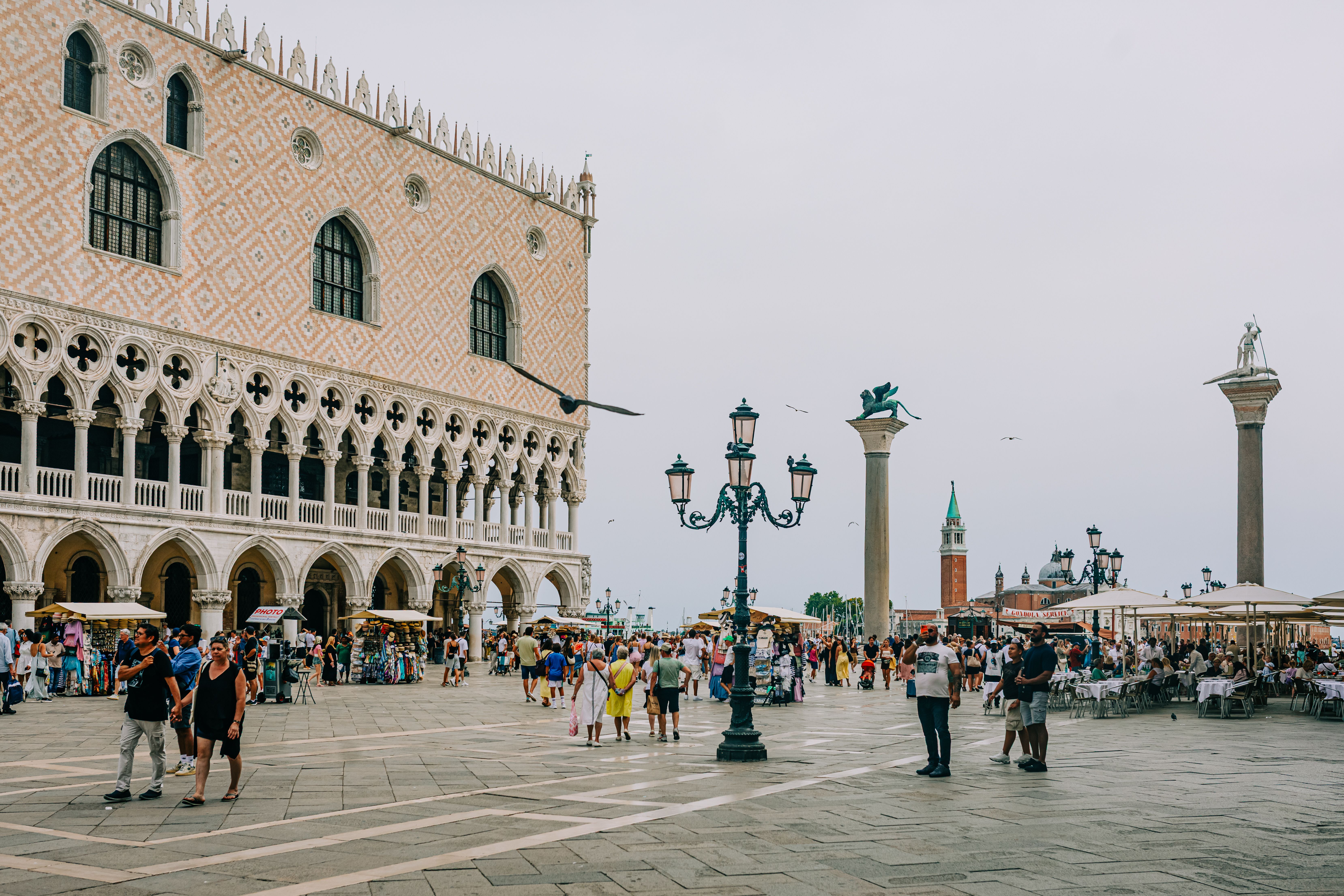 Bustling atmosphere at St. Mark's Square in Venice with tourists under a bright sky.