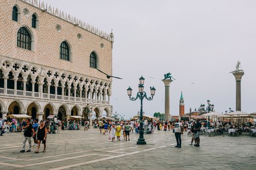 Bustling atmosphere at St. Mark's Square in Venice with tourists under a bright sky.