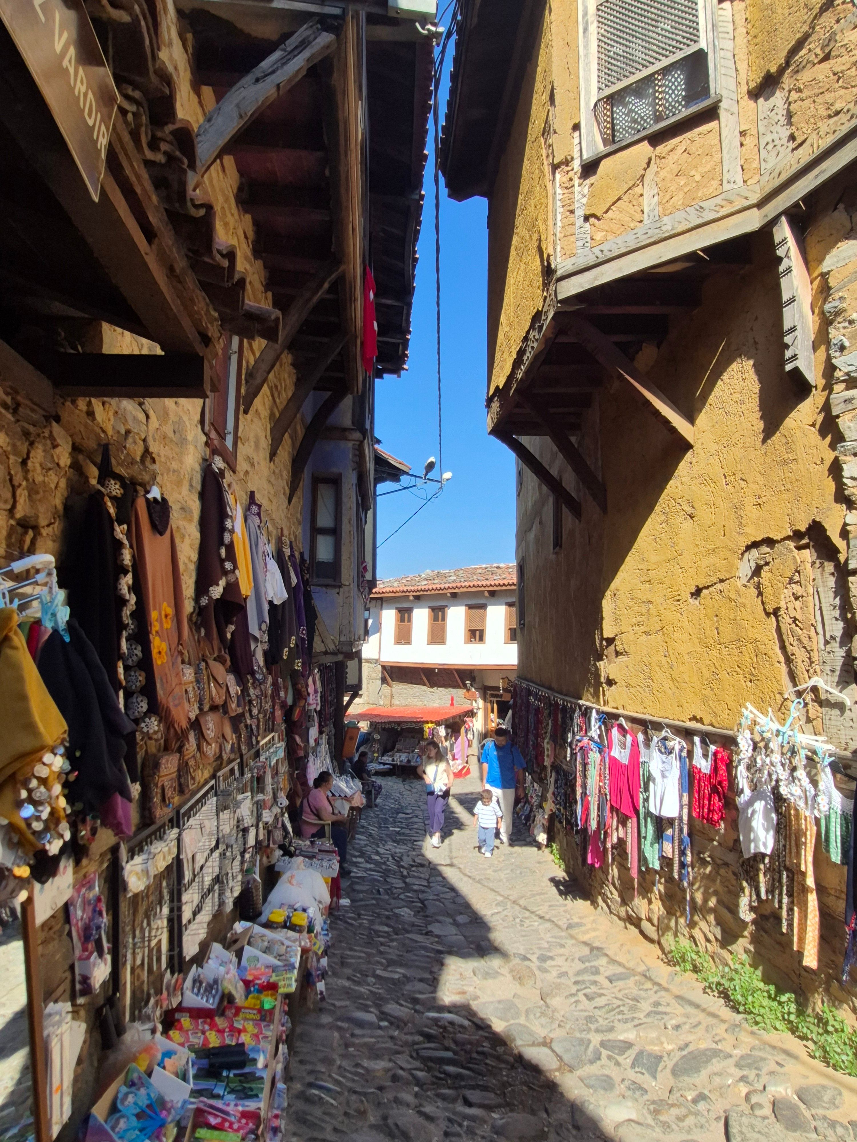 Vibrant outdoor market along a cobblestone street with historic architecture.