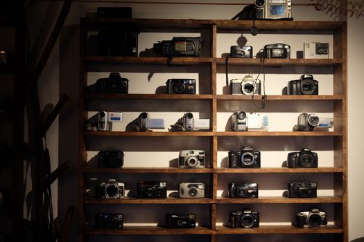 A diverse collection of vintage cameras displayed on rustic wooden shelves.