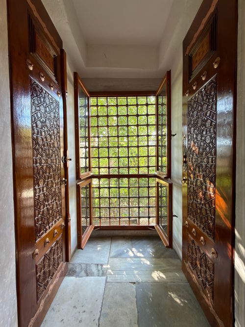 Free Elegant wooden doors opening to a sunny balcony with grid windows, showcasing an ornate design. Stock Photo