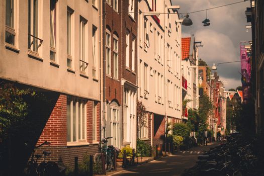 Scenic streetscape of Amsterdam with traditional Dutch architecture and bicycles at dusk.