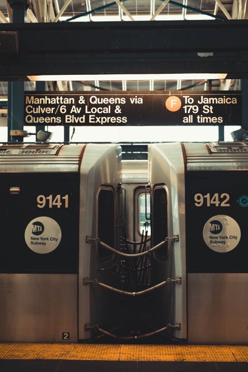 Free Photo of an NYC subway train at a station with directional signage overhead. Stock Photo