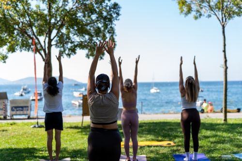 Free Adults practicing yoga outdoors by the sea on a sunny day. Stock Photo