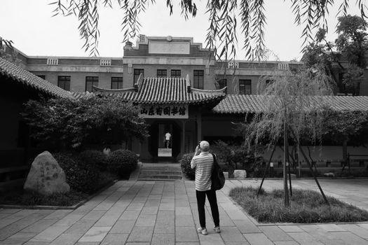 Black and white photo of a visitor exploring a traditional Chinese courtyard museum.