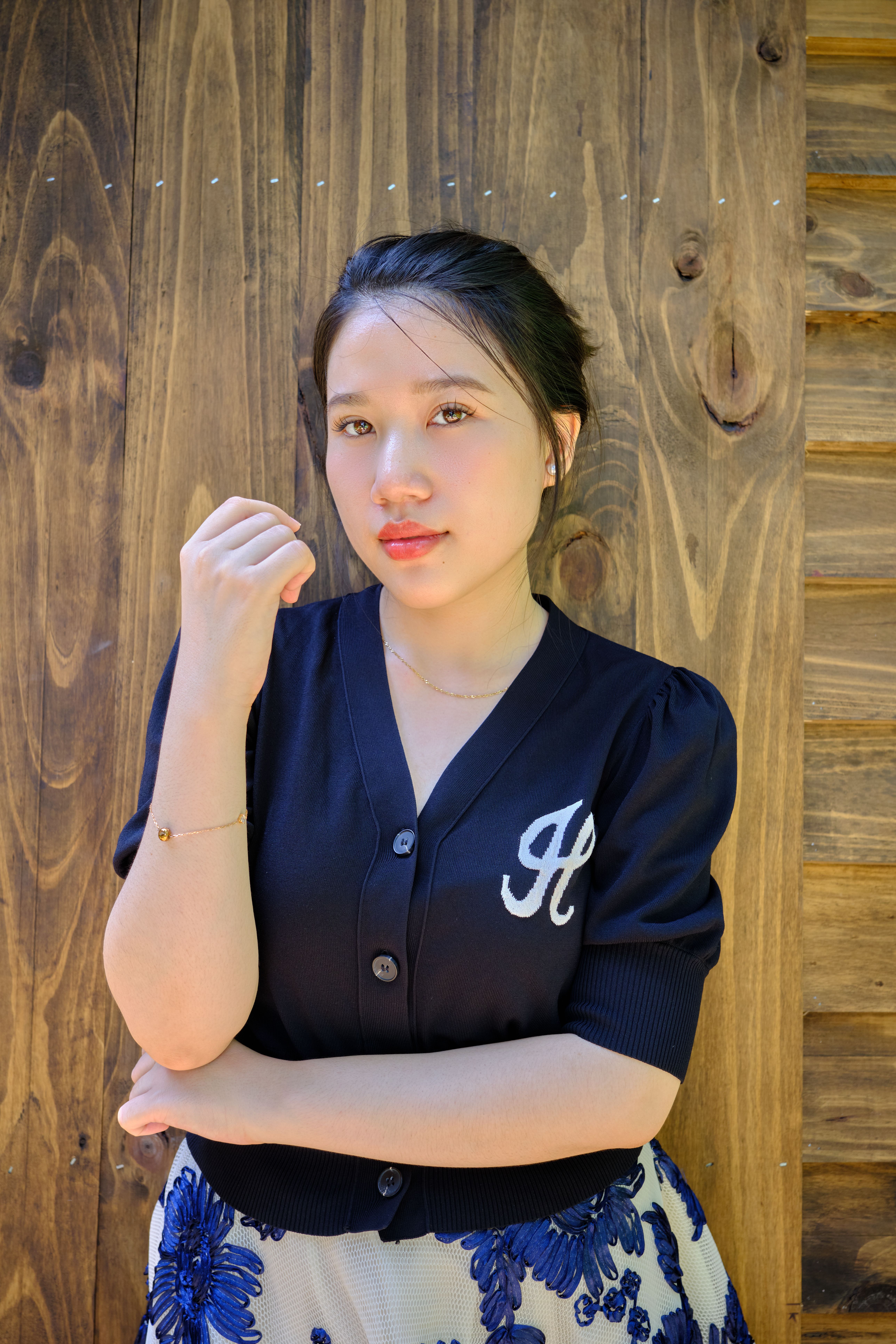 Elegant portrait of a woman standing against a rustic wooden wall.