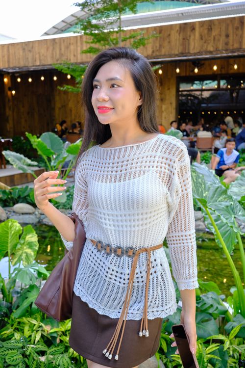 Free A fashionable young woman enjoys a vibrant outdoor cafe setting with lush greenery. Stock Photo