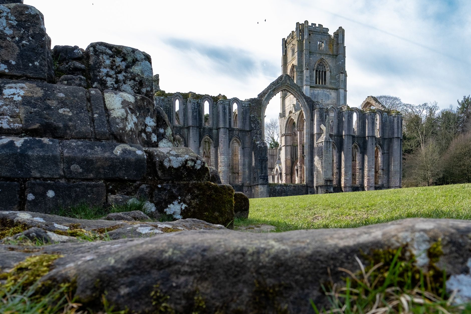 Explore the ancient ruins of Fountains Abbey set in a picturesque landscape, showcasing stunning architecture.
