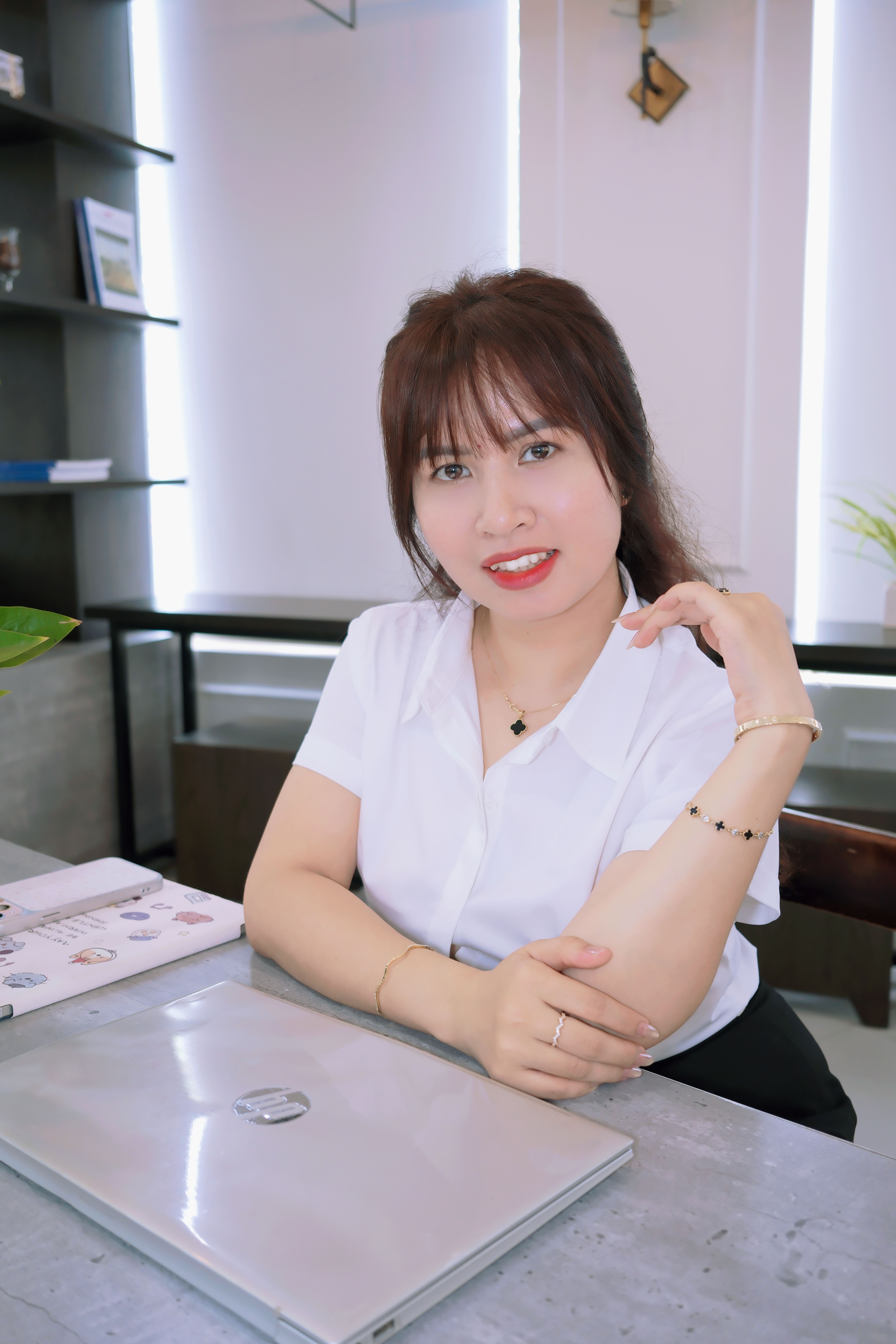 Professional woman in modern office setting, sitting casually with a laptop and brochure.