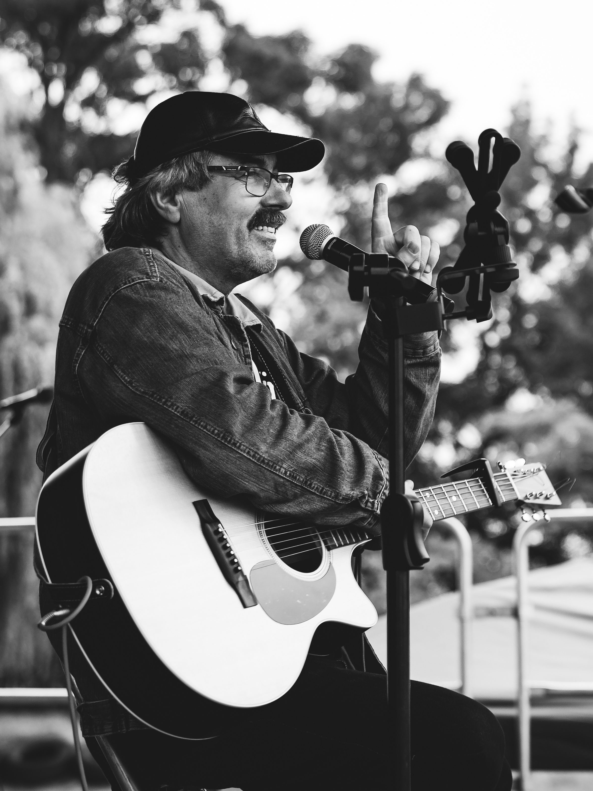 Black and white photo of a guitarist performing with passion in the outdoors.