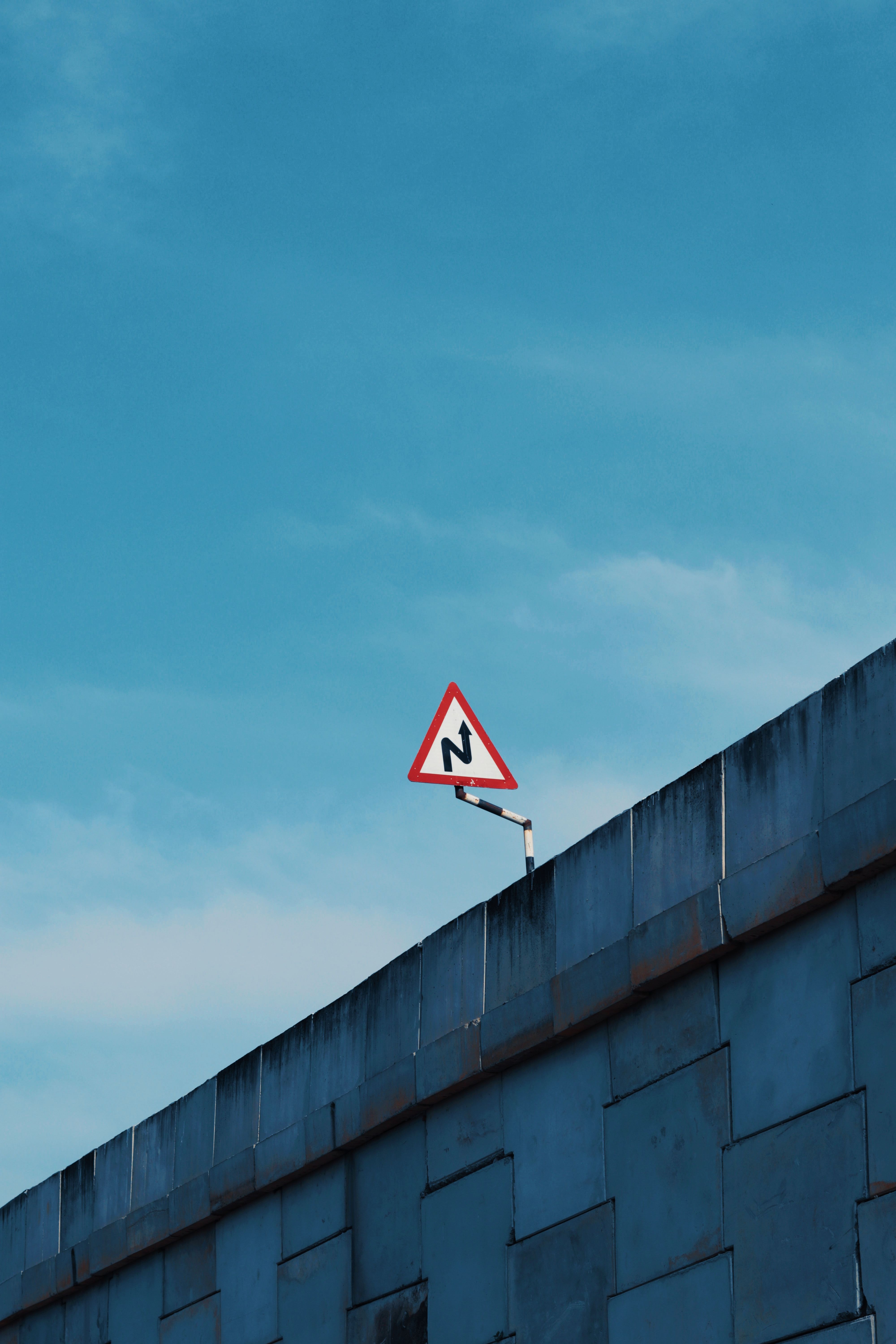 Minimalist shot of a road sign on a building rooftop with blue sky background.